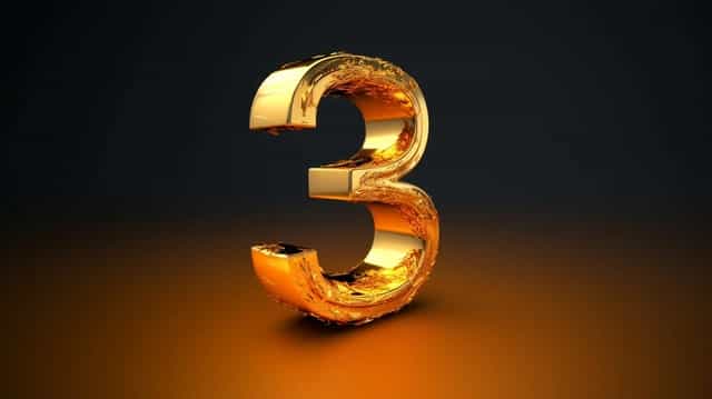 Stylized, shiny golden number '3' with a textured surface, illuminated against a dark background